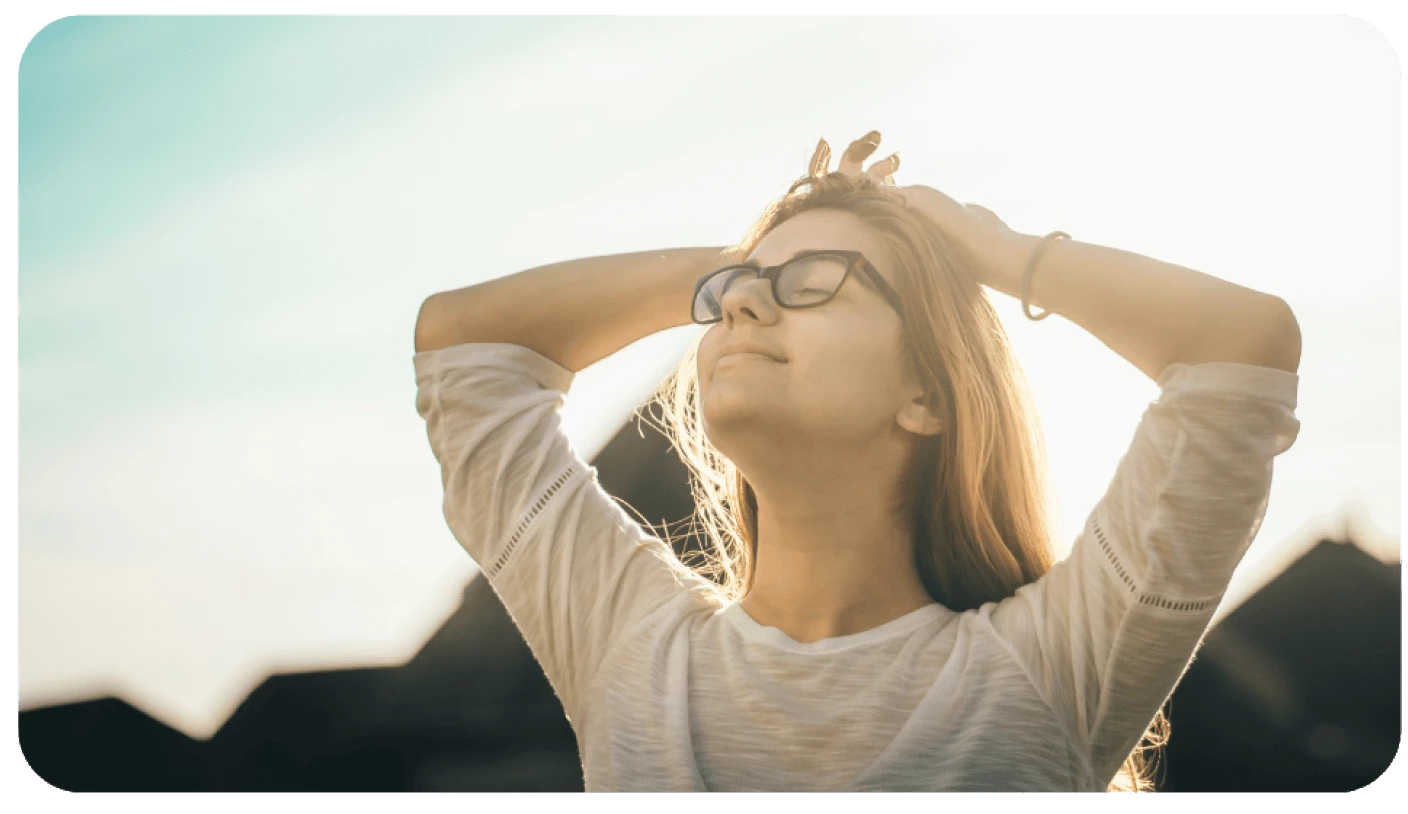 woman smiling up at the sun with her eyes closed